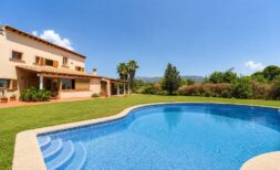 Außenansicht der Finca in Marratxí mit geschwungenem Pool, gepflegtem Rasen und mediterraner Architektur.