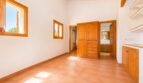 Helles Schlafzimmer der Finca in Marratxí mit Holzbalkendecke, Terrakottaboden und eingebautem Kiefernholzschrank.
