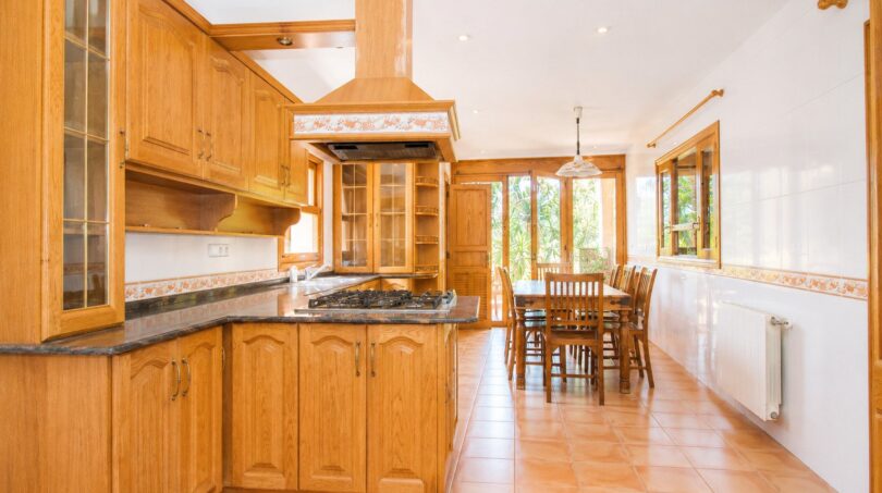 Geräumige Landhaus-Küche mit Holzschränken, Granit-Arbeitsplatten und Essbereich der Finca in Marratxí