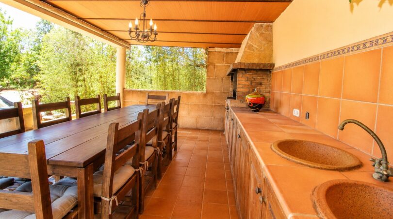 Überdachte Terrasse der Finca mit Grillküche, Doppelwaschbecken und großem Holzesstisch für 8 Personen.