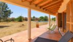 Überdachte Terrasse der Finca in Marratxí mit Holzbalken, Terrakottaboden, Loungestühlen und Blick auf Pool und Garten.