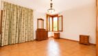 Helles Schlafzimmer der Finca in Marratxí mit Terrakottaboden, Holzmöbeln und floralem Vorhang.