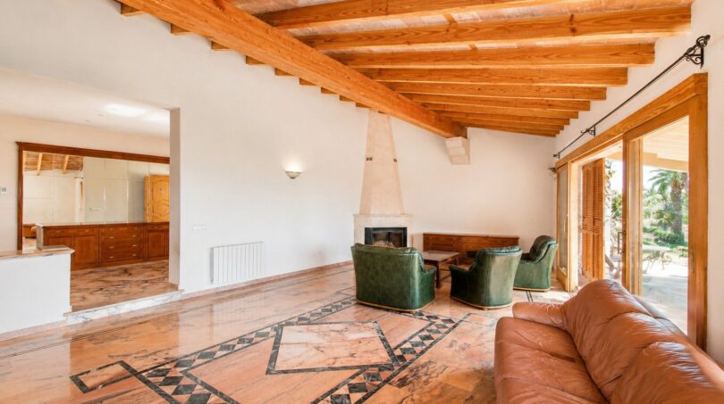 Wohnzimmer der Finca in Marratxí mit Holzbalkendecke, Marmorboden, Kamin und Ledersofas