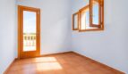 Helles, leeres Zimmer der Finca in Marratxí mit Terrakottaboden, Holztür zum Balkon und geöffnetem Fenster