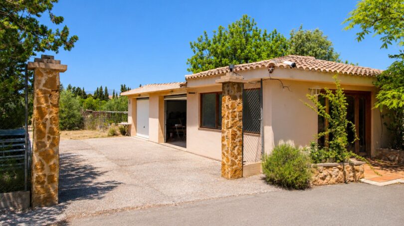Außenansicht der Finca in Marratxí mit Terrakotta-Ziegeldach, Natursteinpfeilern und Garagenzufahrt.