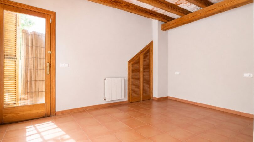 Leeres Zimmer der Finca Marratxí mit Terrakottaboden, Holzbalkendecke und Tür zum Außenbereich