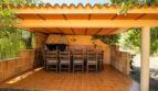 Überdachte Terrasse der Finca Marratxí mit Grillkamin, großem Holztisch und Stühlen für mediterrane Abende.