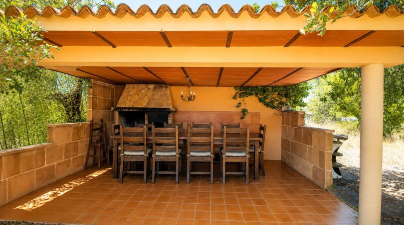 Überdachte Terrasse der Finca Marratxí mit Grillkamin, großem Holztisch und Stühlen für mediterrane Abende.
