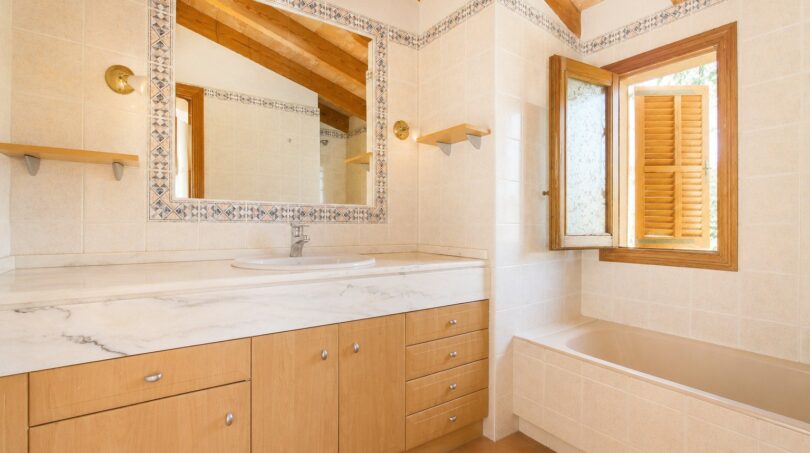 Helles Badezimmer der Finca mit Marmor-Waschtisch, Holzbalkendecke und mediterranen Fliesen in Marratxí.