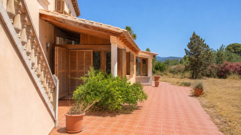 Sonnige Terrasse der Finca in Marratxí mit Terrakottafliesen, Holzläden und mediteraner Bepflanzung