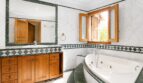 Elegantes Badezimmer der Finca in Marratxí mit Whirlpool, Marmor, grünen Akzenten und Holzschränken.