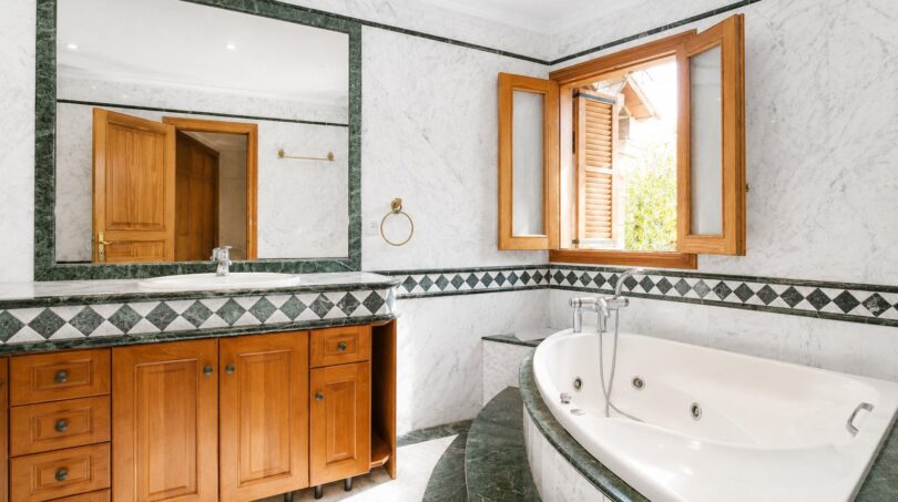Elegantes Badezimmer der Finca in Marratxí mit Whirlpool, Marmor, grünen Akzenten und Holzschränken.