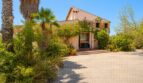 Außenansicht der Finca in Marratxí mit üppiger Begrünung, Palmen und mediterraner Steinfassade.