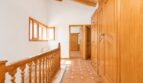 Heller Flur der Finca Marratxí mit Holzbalken, Terrakottaboden, Holzgeländer und eingebauten Holzschränken