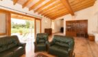Helles Wohnzimmer der Finca in Marratxí mit Holzbalkendecke, grünen Ledersofas und Blick in den Garten.
