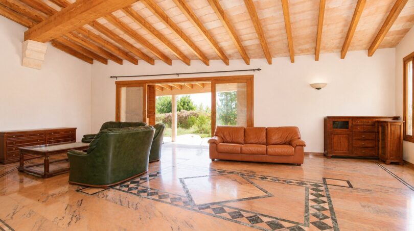 Helles Wohnzimmer der Finca Marratxí mit Holzbalkendecke, Marmorböden und Ledersofas