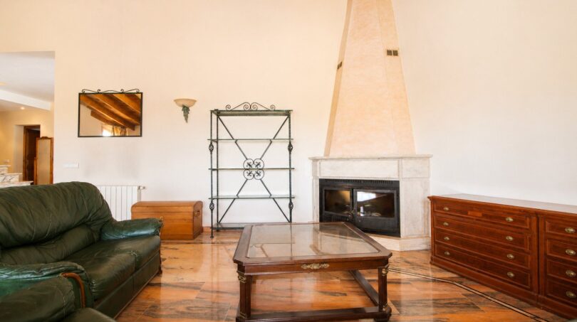Wohnzimmer der Finca in Marratxí mit Kamin, Holzbalkendecke, Ledersofa und Marmorboden.