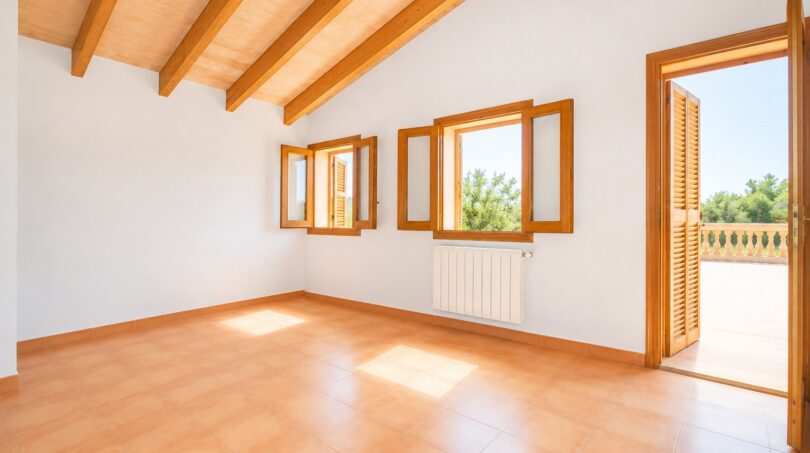 Helles Zimmer der Finca Marratxí mit Holzbalkendecke, Terrakottaboden und Türen zur sonnigen Terrasse.