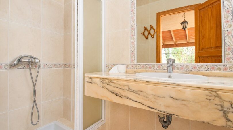 Badezimmer der Finca Marratxí mit Marmor-Waschtisch, Dusche und Fliesenspiegel in mediterranem Stil