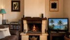 Acogedor salón de la finca Lloseta con chimenea encendida, sofá de cuero y ambiente mediterráneo.