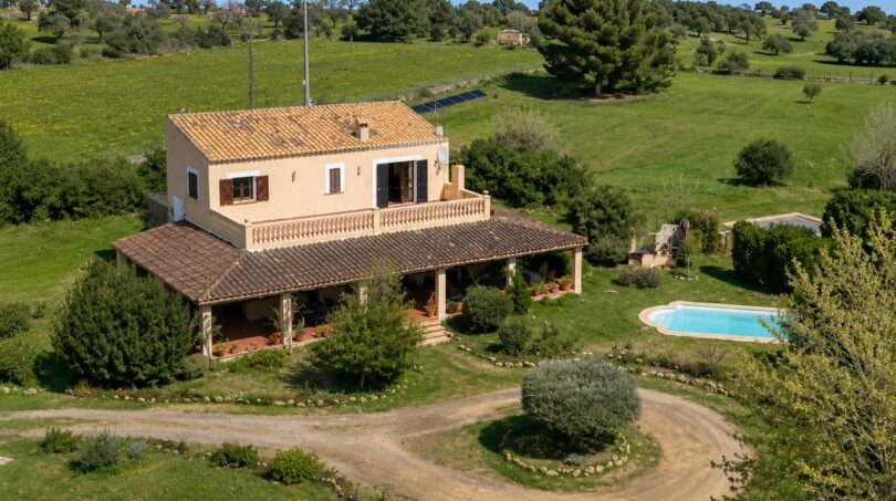 Vista aérea de una finca mallorquina en Lloseta con piscina, veranda y paisaje verde.