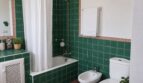 Baño de la finca Lloseta con azulejos verdes, bañera con cortina de ducha, bidé y inodoro