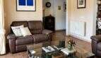 Wohnzimmer der Finca in Lloseta mit Ledersofa, Glastisch, Heizkörper und mediterranem Fliesenboden.