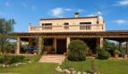 Vista exterior de la finca mallorquina en Lloseta con balcón, terraza y jardín bien cuidado.