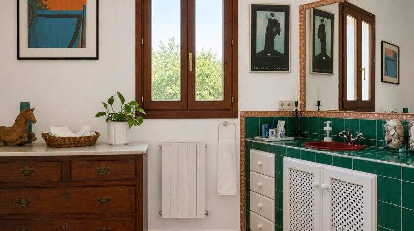 Badezimmer der Finca mit grünen Fliesen, rotem Waschbecken, Holzkommode und rustikalem Charme