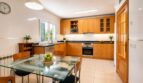 Cocina luminosa con frentes de madera, mesa de cristal y electrodomésticos modernos en dúplex Sa Torre, Llucmajor