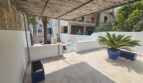 Covered terrace with pool, palm trees and blue ceramic pots of a modern apartment in Portocolom
