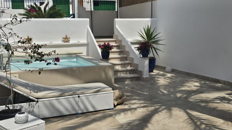 Sunny terrace with jacuzzi, lounge furniture and staircase access in modern apartment in Portocolom