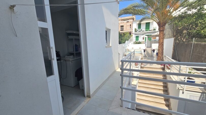 Balcony with utility room, white railing and palm tree in modern apartment in Portocolom