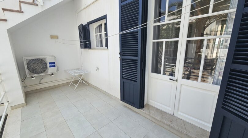 Covered terrace with air conditioning, dark shutters and tiled floor in Portocolom apartment