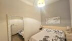Bright bedroom with double bed, gray wall design, large mirror and pendant light in Portocolom apartment