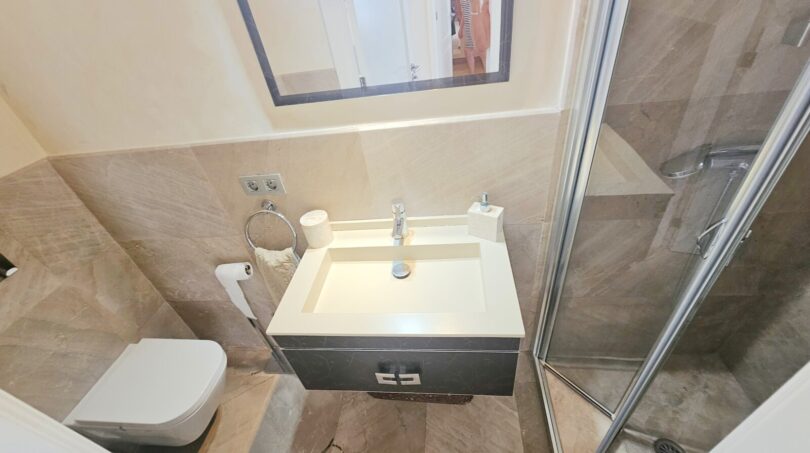 Modern bathroom with shower cubicle, wall-mounted toilet and elegant washbasin in Portocolom apartment