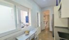 Bright kitchen with small dining table, window to terrace, modern appliances and passage to living area in Portocolom