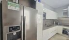 Modern white fitted kitchen with stainless steel side-by-side refrigerator and integrated appliances in Portocolom apartment