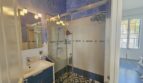 Modern bathroom with glass shower, blue-white tiles and washbasin in the apartment in Portocolom