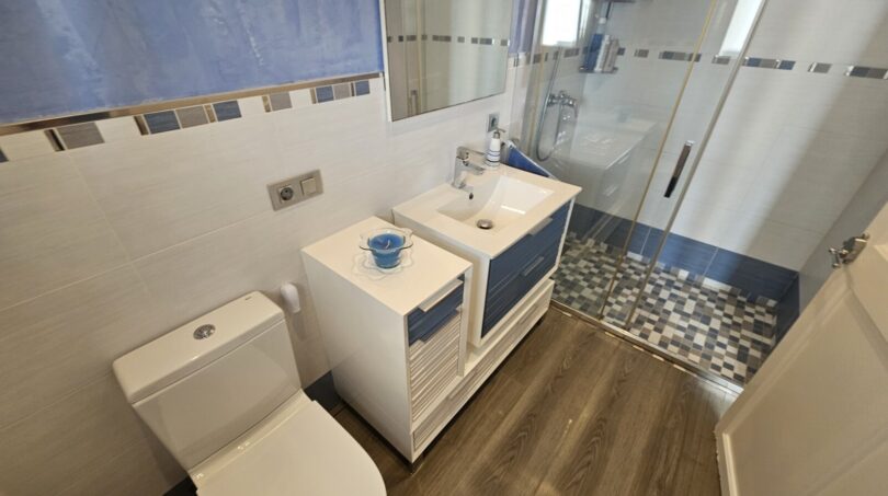 Modern bathroom with shower, washbasin and toilet in blue-white design in Portocolom apartment