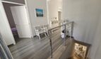 Bright stairwell with chrome railing, wooden floorboards and seating area in modern apartment in Portocolom
