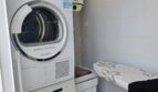 Utility room with stacked washing machine and dryer plus ironing board in modern apartment in Portocolom
