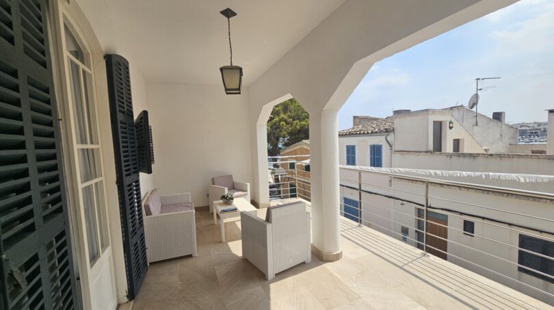 Covered terrace with lounge furniture, archways and view of Portocolom – apartment spanning 2 floors