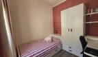 Small bedroom with single bed, white wardrobe and desk, red accent wall, Portocolom apartment