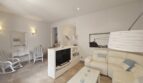 Bright living room with white leather sofa, TV unit and marble floor in modern apartment in Portocolom