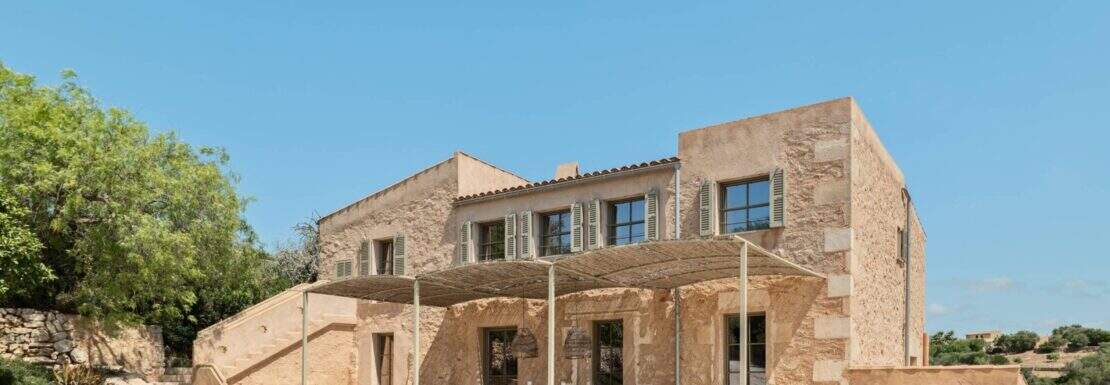 Außenansicht einer exklusiven Finca in Manacor mit Natursteinmassiv, überdachter Terrasse und Holzofen.