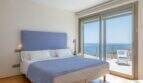 Dormitorio de la villa de lujo con cama doble azul, balcón y vistas espectaculares al mar en Cala Magrana