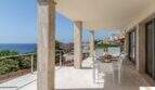 Terraza cubierta con columnas de mármol, conjunto de comedor blanco y vistas al mar de la villa de lujo en Cala Magrana