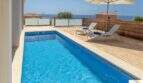 Piscina privada con terraza de madera, tumbonas y vistas al mar de la villa de lujo en Cala Magrana, Porto Cristo