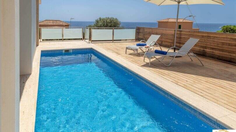 Piscina privada con terraza de madera, tumbonas y vistas al mar de la villa de lujo en Cala Magrana, Porto Cristo
